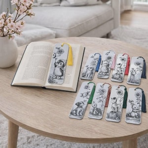 Op de afbeelding: Een verzameling geïllustreerde bladwijzers met verschillende dieren en zonnebloemen. Elke bladwijzer heeft een kwast in een andere kleur. Eén bladwijzer is in een open boek geplaatst. De illustraties zijn in zwart-wit.