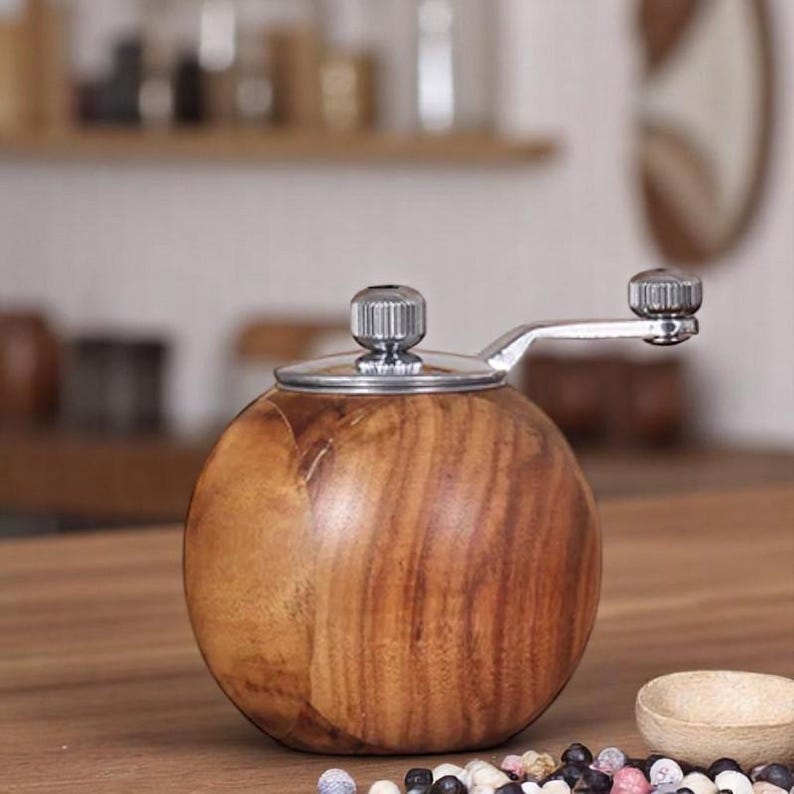 K&ouml;nnte beinhalten: Ein Pfefferm&uuml;hle aus Holz mit silbernem Deckel und Kurbel. Die M&uuml;hle ist rund und hat eine dunkelbraune Holzmaserung.