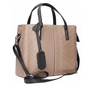 May include: A beige handbag with a snakeskin texture. The bag has black handles and a detachable black shoulder strap. A black tag hangs from the handle. The bag is rectangular with a structured design.
