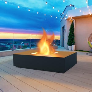 Könnte beinhalten: Ein moderner Außenkamin mit schwarzem Sockel und brennender Flamme. Der Kamin steht auf einer Holzterrasse mit Lichterketten darüber. Ein Hängesessel und Topfpflanzen befinden sich im Hintergrund, mit einer Skyline bei Sonnenuntergang.