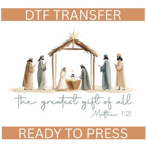 May include: A watercolor illustration of the Nativity scene, featuring Mary, Joseph, baby Jesus, and the three wise men. The text "DTF TRANSFER" and "READY TO PRESS" are at the top and bottom, with "the greatest gift of all" and Matthew 1:21 in the center.