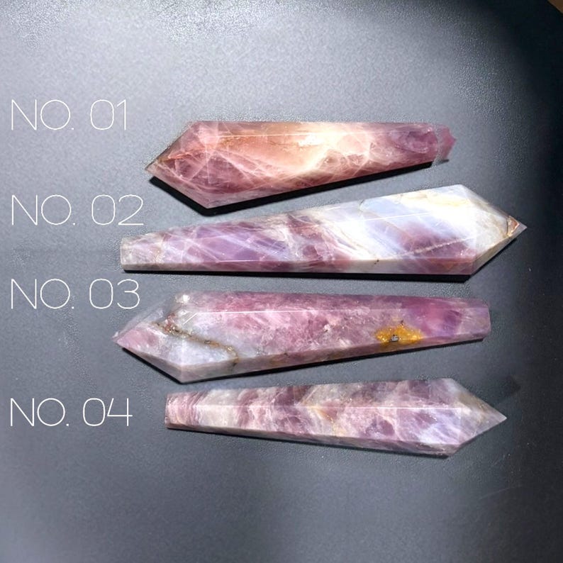 May include: Four polished, faceted crystal wands labeled NO. 01, NO. 02, NO. 03, and NO. 04. Each wand features varying shades of translucent purple, pink, and white mineral inclusions with a pointed tip and a flat, hexagonal base.
