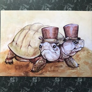 May include: Two painted turtles wearing top hats, one brown and one black, on a light brown background.