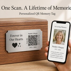 May include: A wooden urn with a metal plaque that reads "Forever in Our Hearts" and includes a QR code. A smartphone displays a photo and text: "In Loving Memory, Natalie S Harper 1971-2016." The text above reads "One Scan. A Lifetime of Memories."
