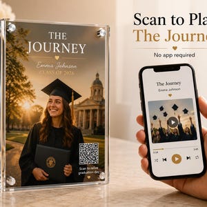 May include: A clear acrylic photo frame with a graduation photo. The frame displays the text "THE JOURNEY" and "Emma Johnson CLASS OF 2026." A smartphone displays a related image and text. The text "Scan to Play The Journey" is also visible.