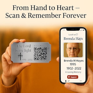 May include: A silver memorial tag with the text "The Lord is my light" and a QR code is held next to a smartphone displaying a memorial page for Brenda Hays. The phone screen shows a photo, name, and dates.
