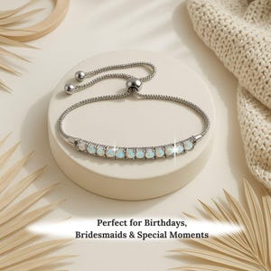 May include: A silver bracelet with a row of oval, opalescent stones. The bracelet has a sliding clasp for adjustable sizing. The text at the bottom reads: Perfect for Birthdays, Bridesmaids & Special Moments.