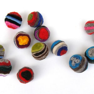 May include: A collection of 12 colorful felt balls, each with a unique pattern of stripes and swirls. The balls are made of wool and are approximately 2 inches in diameter.