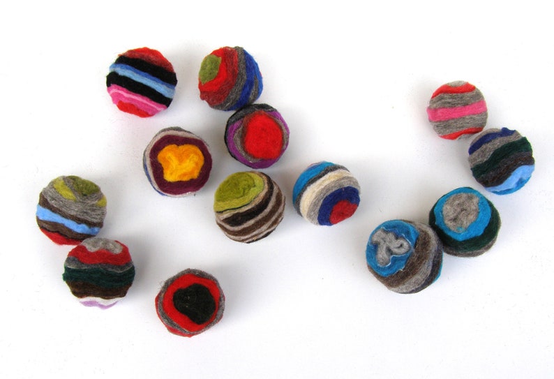 May include: A collection of 12 colorful felt balls, each with a unique pattern of stripes and swirls. The balls are made of wool and are approximately 2 inches in diameter.