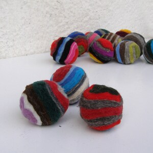 May include: A group of colorful, striped felt balls. The balls are made of wool and are perfect for playing with or decorating a room.