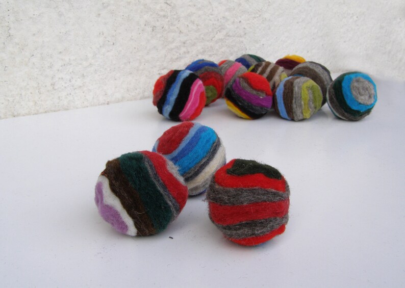 May include: A group of colorful, striped felt balls. The balls are made of wool and are perfect for playing with or decorating a room.