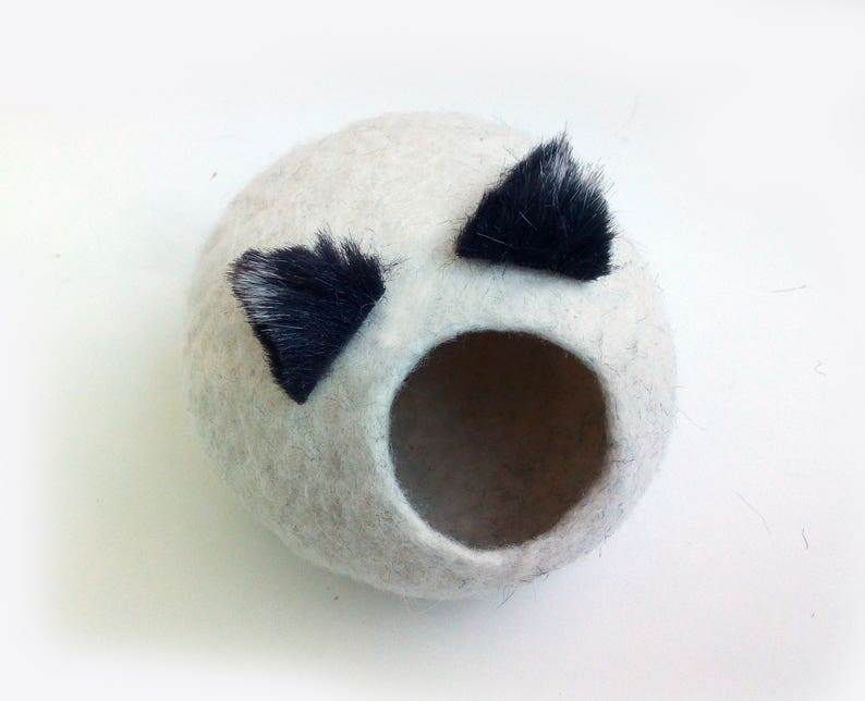 May include: A white felt cat bed with two black felt ears. The bed has a round opening for the cat to enter.