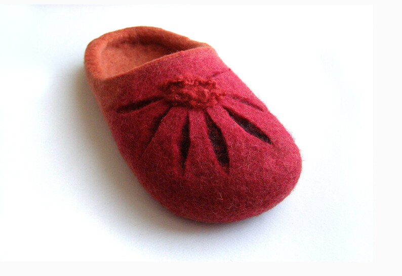 May include: Red felt slippers with a flower design cut out of the fabric.