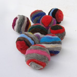 K&ouml;nnte beinhalten: Eine Sammlung bunter, gestreifter Filzkugeln. Die Kugeln sind aus Wolle und haben einen Durchmesser von etwa 5 cm. Sie sind perfekt, um jedem Raum einen Hauch von Farbe und Textur zu verleihen.
