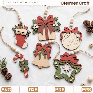 Puede incluir: Un conjunto de seis adornos navideños de madera que incluyen un calcetín, un regalo, una bola, un bastón de caramelo, una campana y una estrella, decorados con lazos rojos y follaje verde, colgados de cuerdas con cuentas de madera. Texto: CleimenCraft.