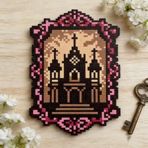 Puede incluir: Una pieza de arte pixelado que representa una iglesia gótica con una cruz, enmarcada en rosa y negro. La obra de arte está hecha de pequeñas cuentas de colores, sobre un fondo marrón claro. También se ve una llave antigua y flores blancas.