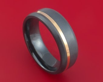 May include: A dark gray wedding band with a thin gold band inset into the surface.