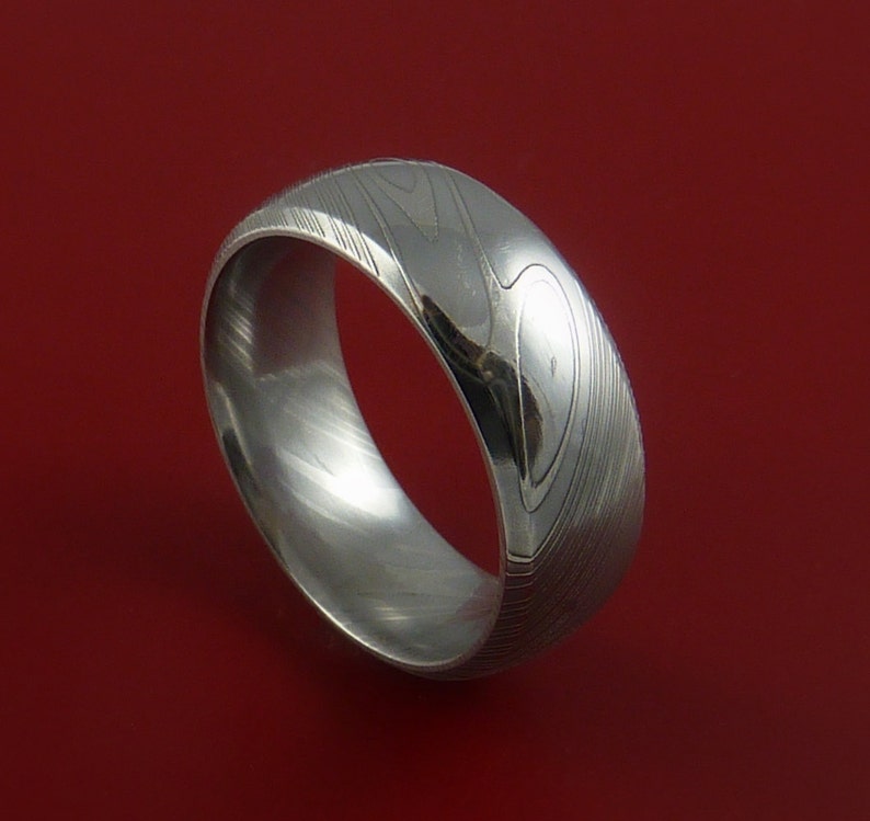 May include: A silver ring with a unique, swirling pattern. The ring is made of metal and has a polished finish.