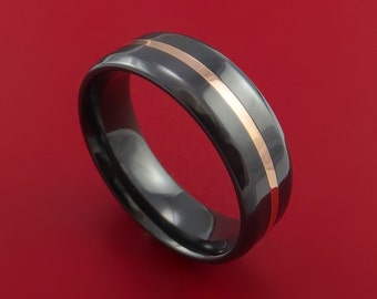 May include: A black ceramic wedding band with a thin rose gold inlay. The band has a polished finish and a comfortable fit.