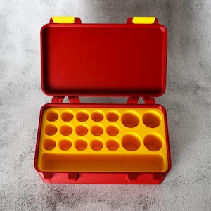 May include: Open red toolbox with yellow interior and compartments. The toolbox is rectangular with a hinged lid and yellow latches. The interior has multiple circular compartments and a long rectangular compartment.