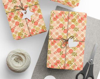 May include: Three gift boxes wrapped in floral patterned paper with pink and orange flowers on a cream background. The boxes are tied with twine and have white paper tags attached.