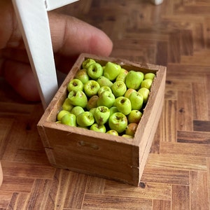 May include: A wooden crate filled with green apples. The crate is made of unfinished wood and has a rustic look.