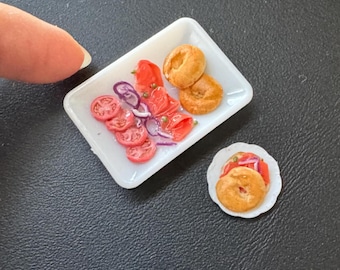 Miniatuurpoppenhuis-bagel met lox-schaal op een plastic bord in 1:12-brunchontbijt