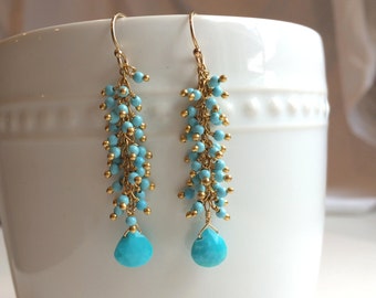 May include: Gold dangle earrings with turquoise beads and a teardrop-shaped turquoise stone at the bottom.