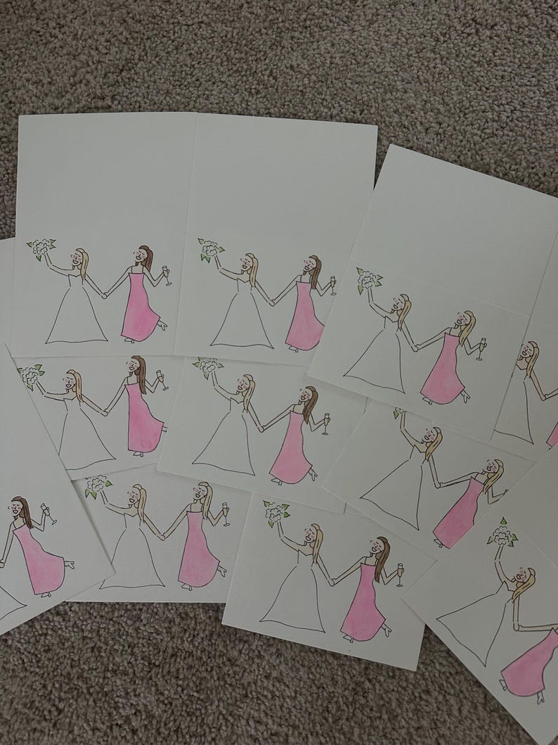Puede incluir: Una colecci&oacute;n de tarjetas de felicitaci&oacute;n rectangulares blancas con una ilustraci&oacute;n dibujada a mano de dos figuras tomadas de la mano. Una figura viste un vestido blanco y sostiene un ramo, mientras la otra viste un vestido rosa y una copa.