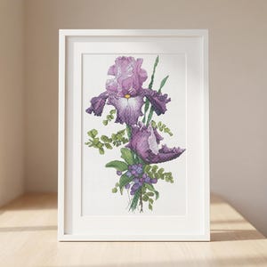 May include: A framed print featuring a watercolor illustration of purple iris flowers. The artwork showcases detailed petals, green foliage, and small purple berries. The white frame is displayed on a wooden surface near a window.