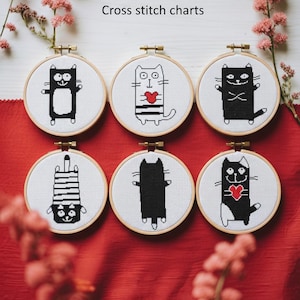 May include: Six round cross-stitch charts featuring black and white cat designs. Each cat is unique, with different poses and patterns, some with hearts. The charts are set in wooden embroidery hoops, with the text "Black and white cats Cross stitch charts" above.