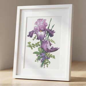 Pu&ograve; includere: Una stampa ad acquerello incorniciata di fiori di iris viola. L'opera presenta una rappresentazione dettagliata dell'iris, con i suoi distintivi petali e il fogliame verde. La stampa &egrave; incorniciata in una cornice bianca, esposta su una superficie di legno.