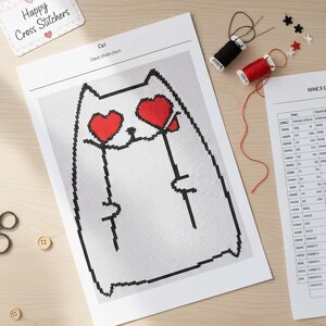 Puede incluir: Un patrón de punto de cruz con un gato con ojos en forma de corazón. Se muestran las palabras "Descarga instantánea" y "¡Fácil y divertido!". La imagen incluye carretes de hilo, tijeras y otros suministros de manualidades.