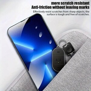 May include: A black smartphone with a blue and white abstract design on the screen is lying on a gray fabric surface. A black key chain with a small black remote control is partially visible in the pocket of the fabric surface.