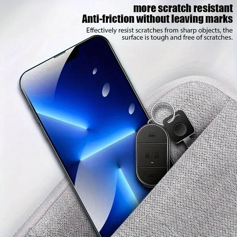 May include: A black smartphone with a blue and white abstract design on the screen is lying on a gray fabric surface. A black key chain with a small black remote control is partially visible in the pocket of the fabric surface.