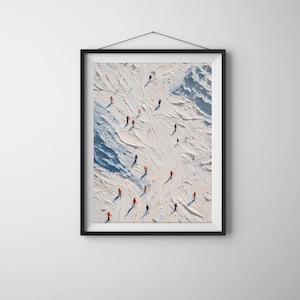 Könnte beinhalten: Gerahmter Kunstdruck, der eine schneebedeckte Berglandschaft mit Skifahrern zeigt. Das Kunstwerk zeigt eine strukturierte weiße und blaue Landschaft mit kleinen Figuren in farbenfroher Skikleidung. Der schwarze Rahmen verleiht dem Wintersportthema eine moderne Note.