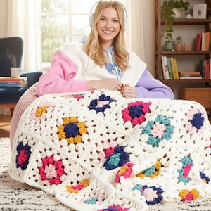 Peut inclure: Une couverture au crochet faite à la main, de couleur blanc cassé, ornée de motifs floraux colorés en rose, bleu, jaune et turquoise. La couverture est drapée sur une surface, mettant en valeur son design et sa texture détaillés. Un élément de décoration intérieure douillet.