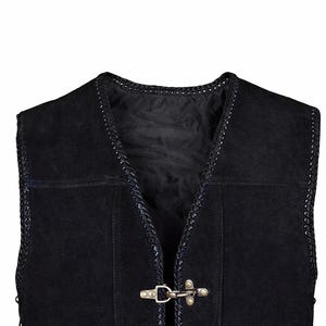 Close-up image of the upper front section of a black suede leather vest, highlighting antique brass hook closures and braided trim detail along the neckline. The soft suede texture and polyester inner lining are visible, emphasizing craftsmanship and durability for biker or casual wear.