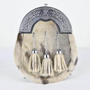 May include: A traditional Scottish sporran with a fur body in shades of cream, brown, and gray. The silver-toned cantle features intricate Celtic knotwork. Three silver chains with matching tassels hang from the cantle, adding a decorative touch.