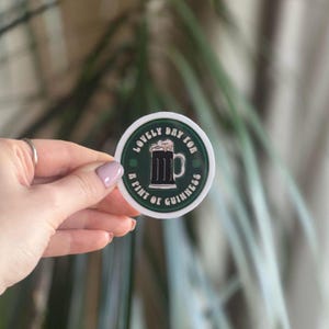May include: A white circular sticker with green text that reads "Lovely Day for a Pint of Guinness". The sticker features a black and white illustration of a pint of Guinness.