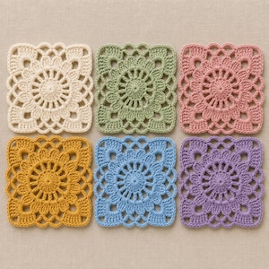 May include: A set of six square crochet coasters arranged in two rows. Each coaster features a circular floral pattern in the center with a scalloped border. The colors include cream, sage green, dusty rose, mustard yellow, sky blue, and lavender.