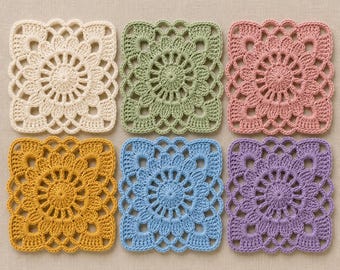 May include: A set of six square crochet coasters arranged in two rows. Each coaster features a circular floral pattern in the center with a scalloped border. The colors include cream, sage green, dusty rose, mustard yellow, sky blue, and lavender.