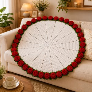 May include: A circular white crochet doily featuring a central radial pattern and a decorative border composed of numerous three-dimensional red roses with green leaves, creating a textured floral edge around the entire circumference.