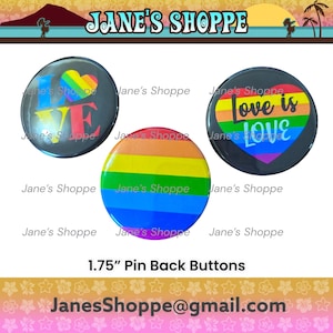 May include: Three pin-back buttons with pride-themed designs. One button features the word "LOVE" with a rainbow heart, another has a rainbow stripe design, and the third says "Love is Love" in a heart shape. Each button is 1.75 inches in diameter.