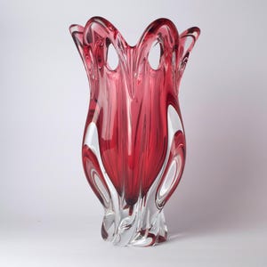 Peut inclure: Un vase en verre élégant, de forme tulipe, avec une couleur rouge vif au centre et du verre transparent sur les bords. Le vase présente des boucles ouvertes en haut et une base torsadée. Design élégant et attrayant.