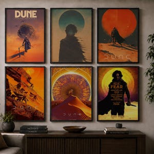 May include: A set of six rectangular wall art prints featuring Dune-themed illustrations in black frames. The posters display various desert landscapes, silhouettes of characters, and large planetary or sun motifs in shades of orange, yellow, and blue.