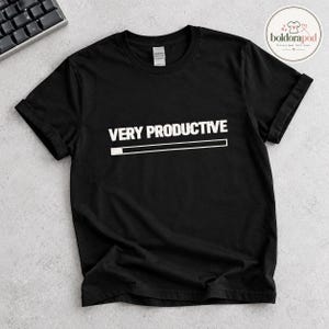 Puede incluir: Una camiseta negra de manga corta con el texto blanco "VERY PRODUCTIVE" centrado en el pecho, situado sobre un gráfico de barra de carga horizontal blanca parcialmente relleno en el lado izquierdo con un bloque blanco sólido.
