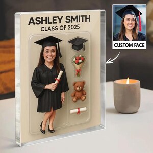 May include: A graduation-themed acrylic block featuring a figure in a cap and gown, holding a diploma. The block includes the name "ASHLEY SMITH" and "CLASS OF 2025". Additional elements include a mortarboard, bouquet, teddy bear, and a small diploma.