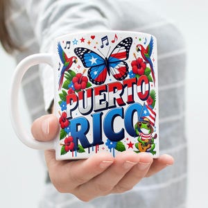 Könnte beinhalten: Weiße Keramik-Tasse mit einem farbenfrohen Design mit den Worten "Puerto Rico". Das Design umfasst einen Schmetterling, Papageien, Hibiskusblüten, Noten und einen Frosch, der Gitarre spielt, alles in leuchtenden Farben.