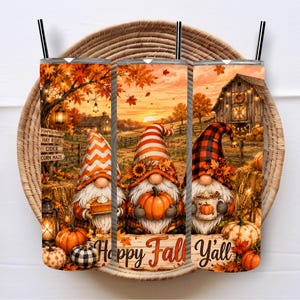 May include: A cylindrical tumbler featuring a fall-themed graphic with three gnomes, pumpkins, a rustic barn, and autumn foliage. The design includes text reading "Happy Fall Y'all" and a signpost listing "Pumpkin Patch," "Hay Rides," "Cider," and "Corn Maze."